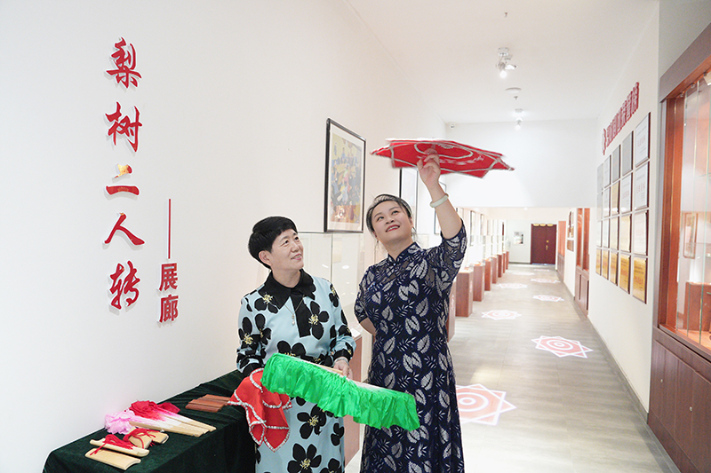 2023年6月29日，在吉林省梨樹(shù)縣地方戲曲劇團(tuán)梨樹(shù)二人轉(zhuǎn)展廊，團(tuán)長(zhǎng)趙丹丹（右一）為作家龔保華講解二人轉(zhuǎn)技巧。